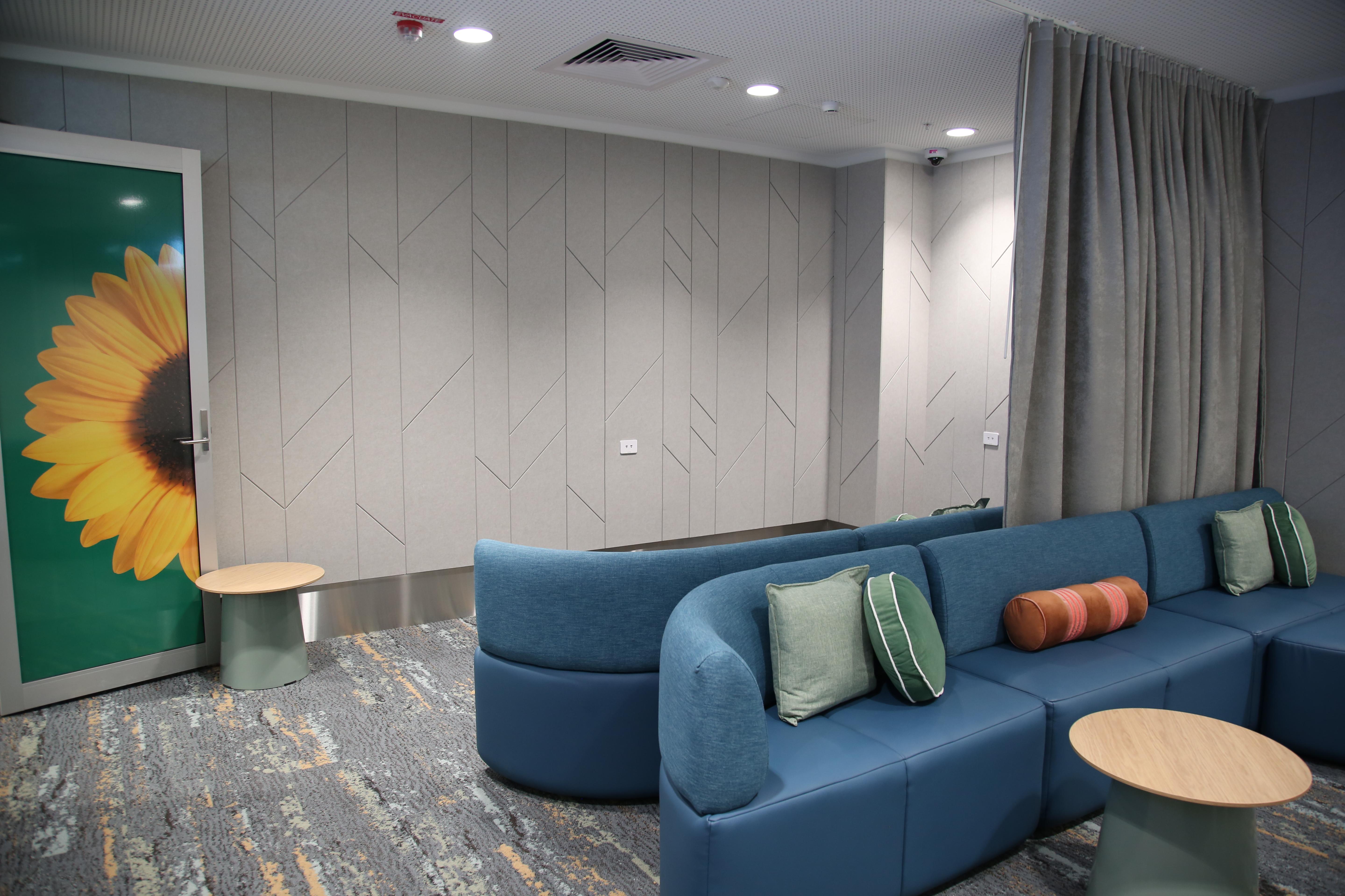 A Quiet Room with curved blue seating, soft cushions, small tables and a curtain divider.